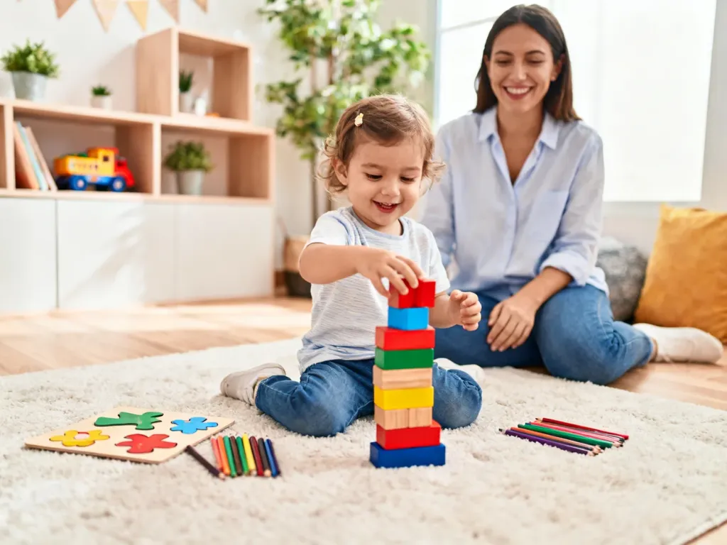 Trzylatek układa klocki i puzzle na dywanie, bawiąc się kreatywnie pod opieką dorosłego w przytulnym, bezpiecznym salonie.